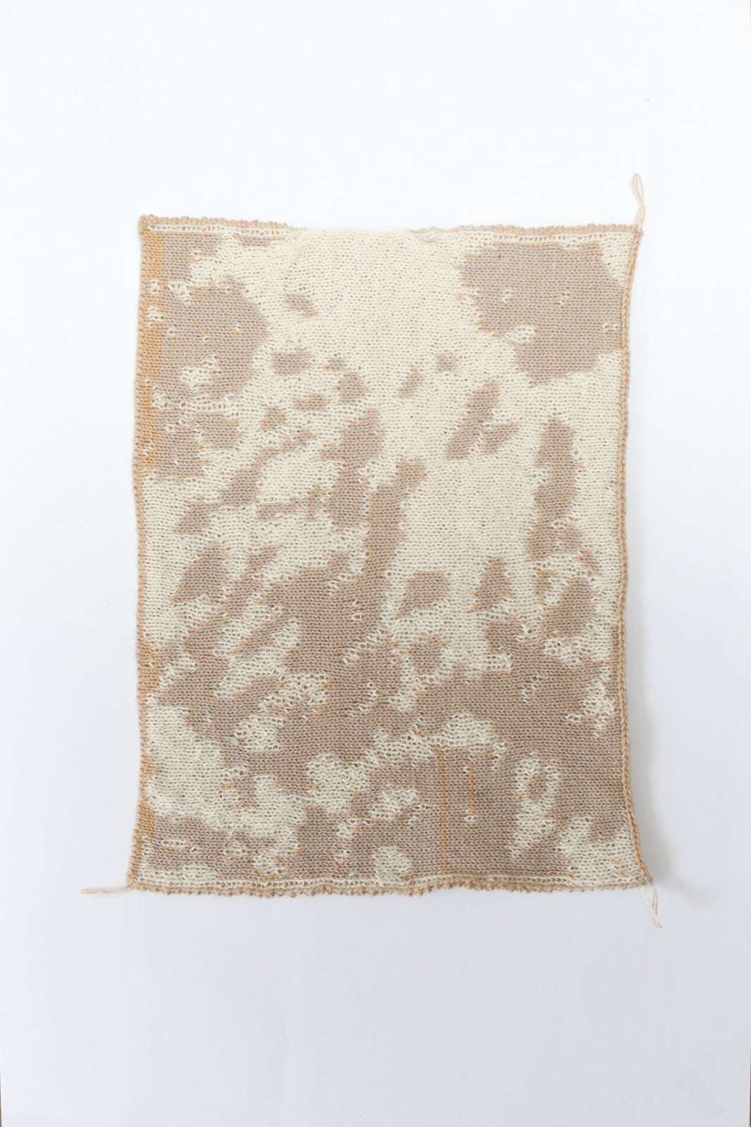 Cow patterned cream and tan knit swatch on a white background