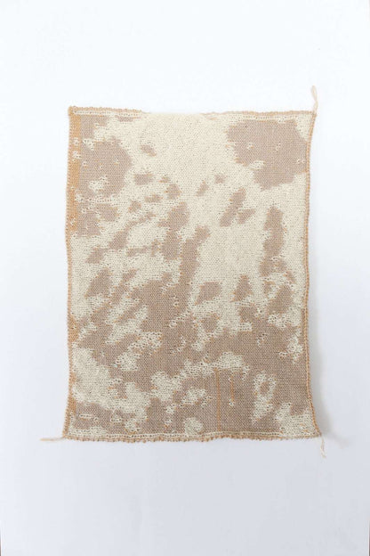 Cow patterned cream and tan knit swatch on a white background