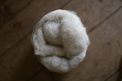 Clump of white Beaurivage Canadian wool on a wooden surface