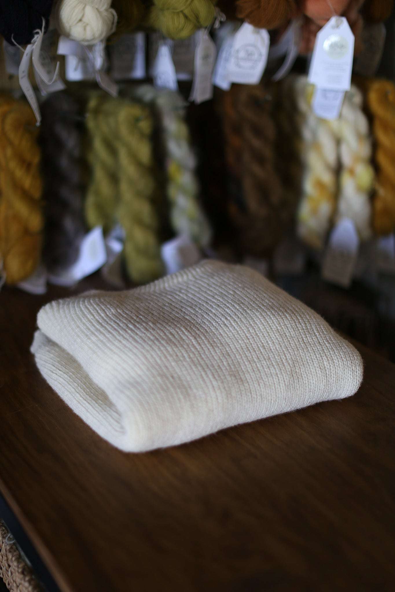 Still life of the Beaurivage sweater, handcrafted from Canadian wool, from Beaurivage farm, surrounded by balls of yarn