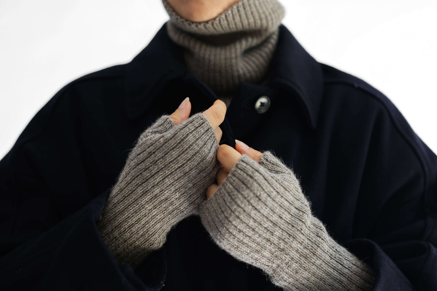 Close-up of a person wearing taupe alpaca knitted hand warmer set against a plain white background.