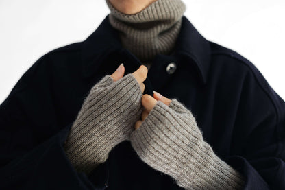 Close-up of a person wearing taupe alpaca knitted hand warmer set against a plain white background.