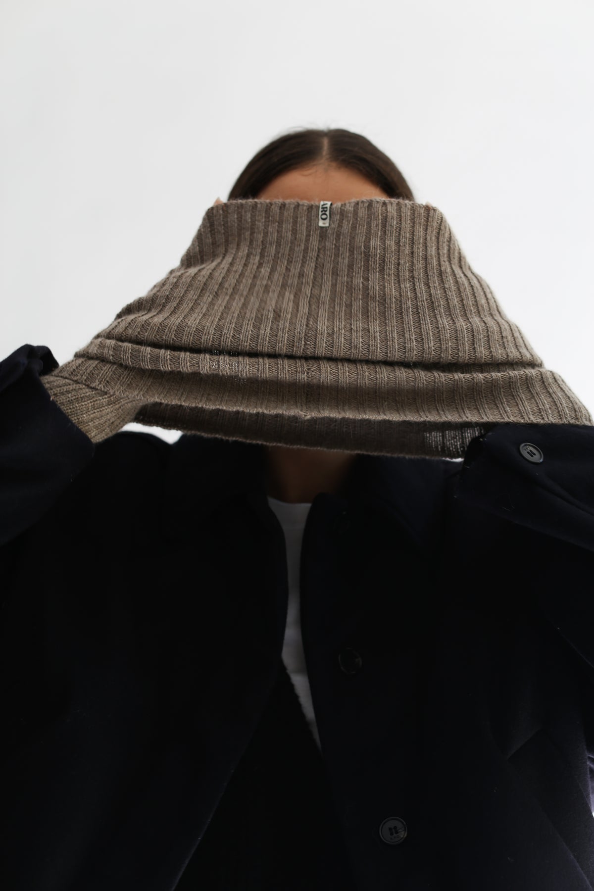 Close-up of a person wearing taupe alpaca knitted hand warmer set and neck warmer against a plain white background.