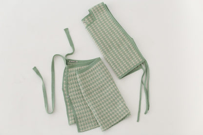 White and green houndstooth knitted apron with matching skirt on a light gray background