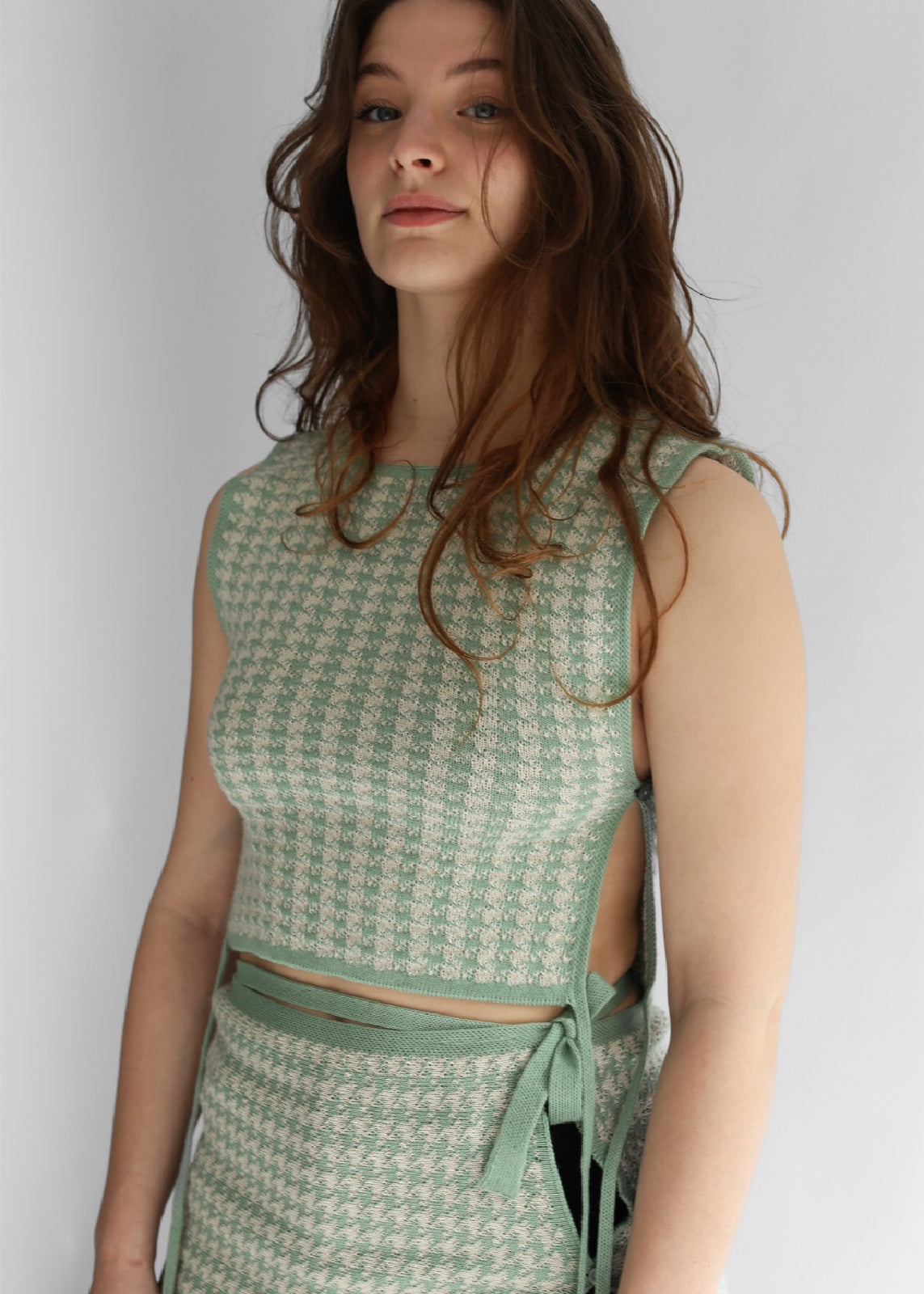 A woman wearing white and green houndstooth knit apron and skirt 