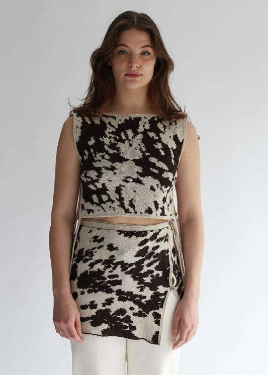Model wearing a cow patterned top and skirt set on a plain background