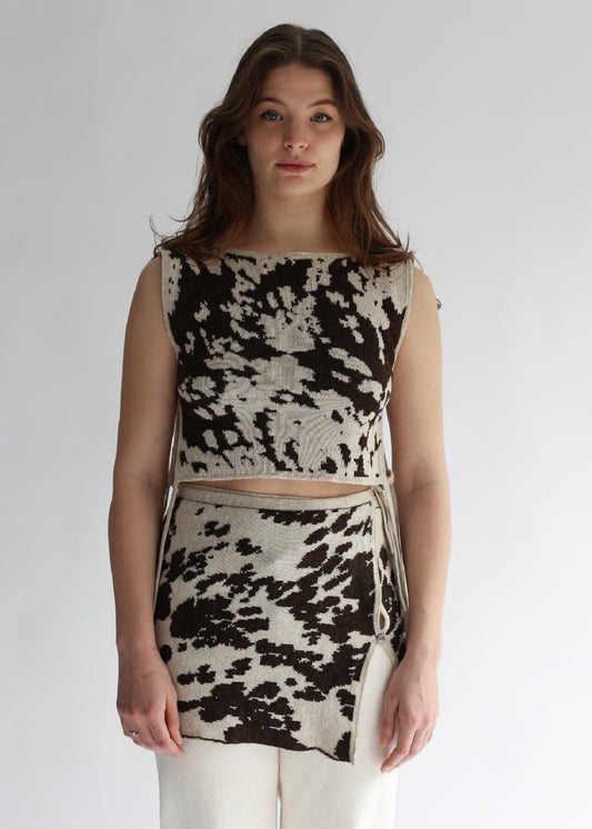 Model wearing a cow patterned top and skirt set on a plain background