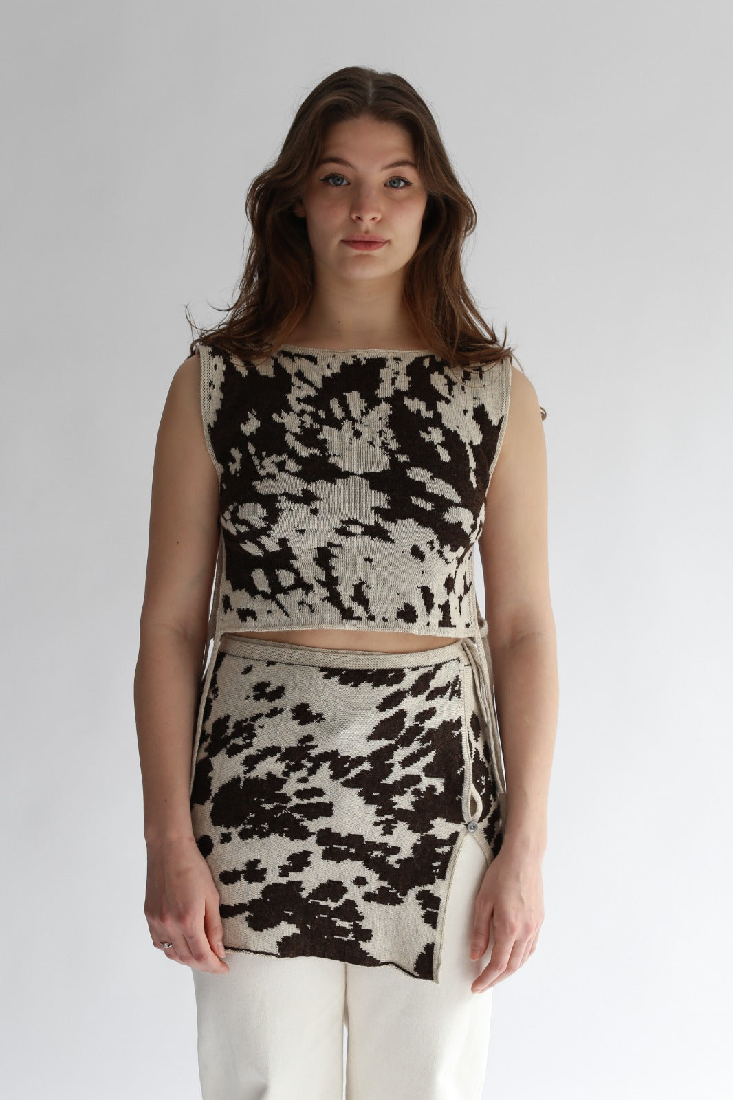 Model wearing a cow patterned top and skirt set on a plain background