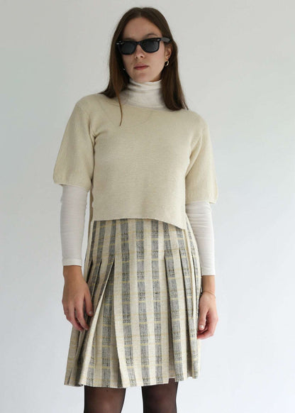 Model wearing the belacaro beige apron with sleeves knit handmade in Canada from baby alpaca