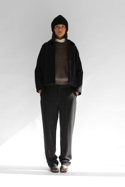 Belacaro beanie in black baby alpaca, ribbed knit with folded brim, worn by model with dark outerwear, full body shot