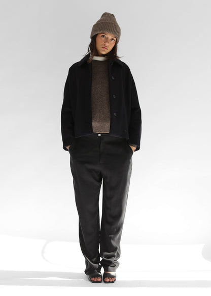 Model wearing the Belacaro kids beanie in grey baby alpaca, styled with a black wool short jacket and baggy grey pants, front view.