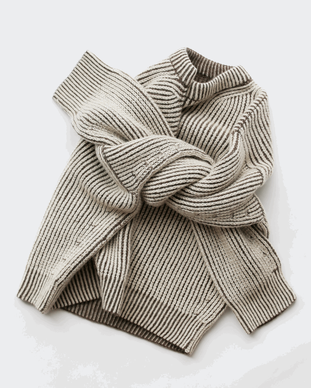 A cream and brown reversible sweater made out of heavy ribs stitches, with arms crossed