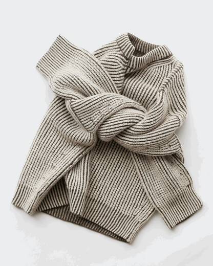 A cream and brown reversible sweater made out of heavy ribs stitches, with arms crossed