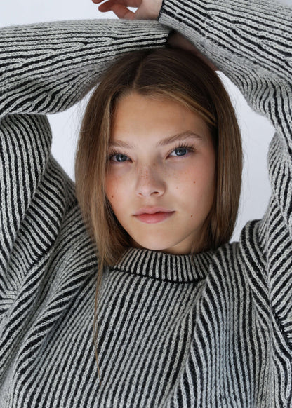 Close-up of a model wearing a bicolor reversible crewneck sweater