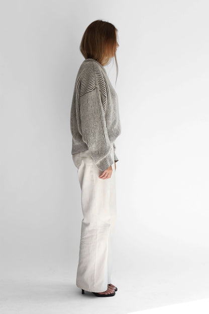 Model wearing a bicolor reversible crewneck sweater from the side against a white background