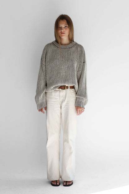 Model wearing a bicolor reversible crewneck sweater from the front against a white background
