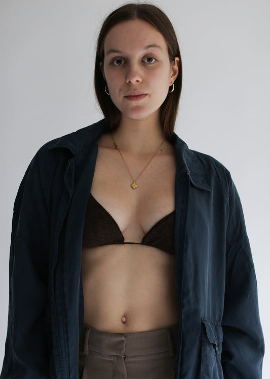 Woman wearing a dark jacket over a brown bralette on a plain background