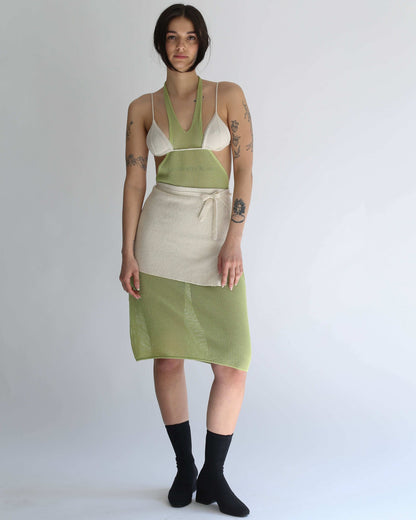 Woman wearing a green knit dress, white knit bikini and white knit skirt