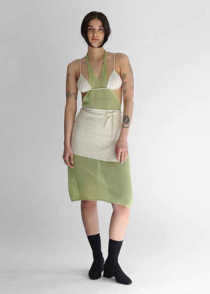 Woman wearing a green knit dress, white knit bikini and white knit skirt