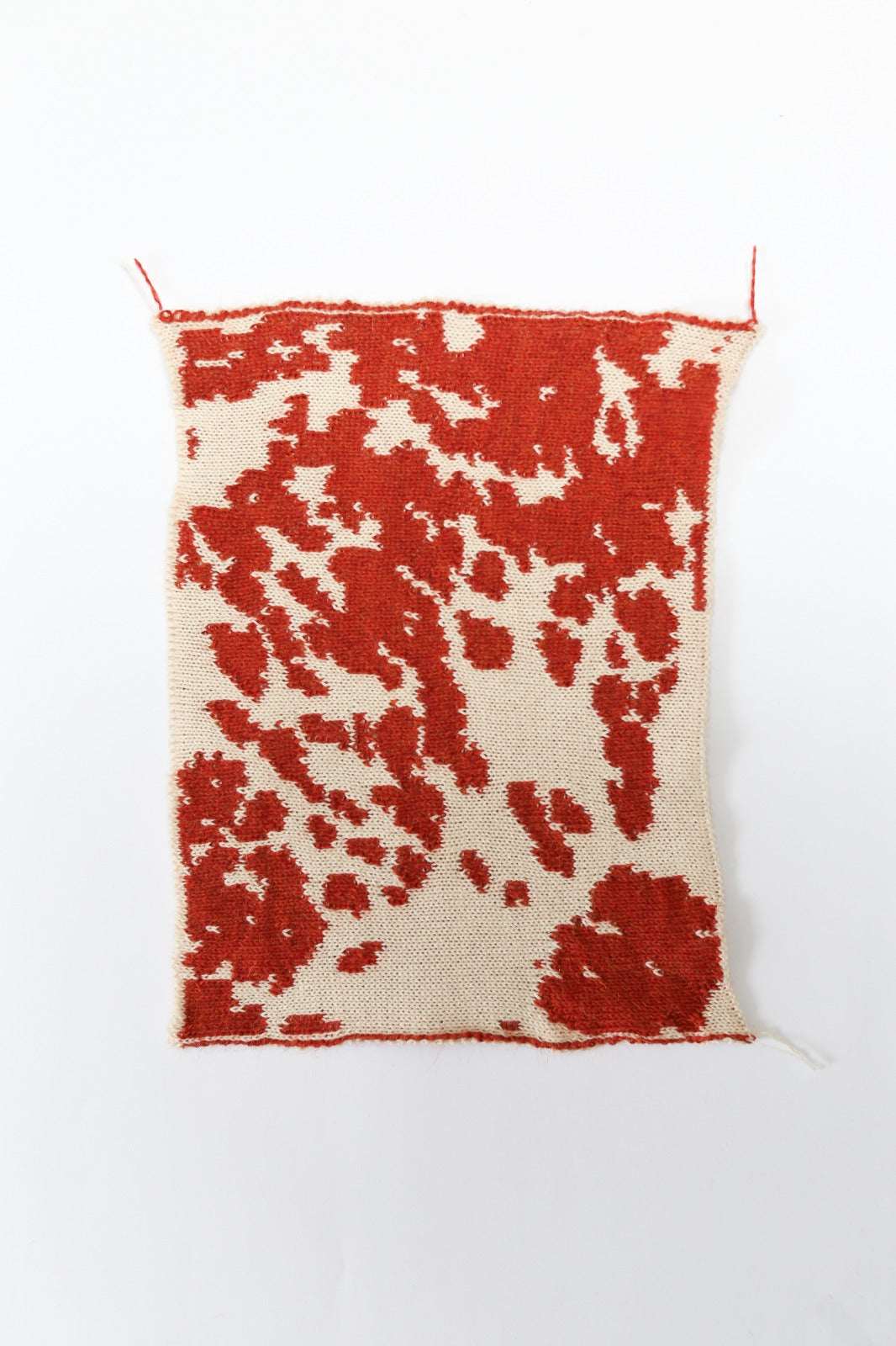 Cow patterned cream and red knit swatch on a white background