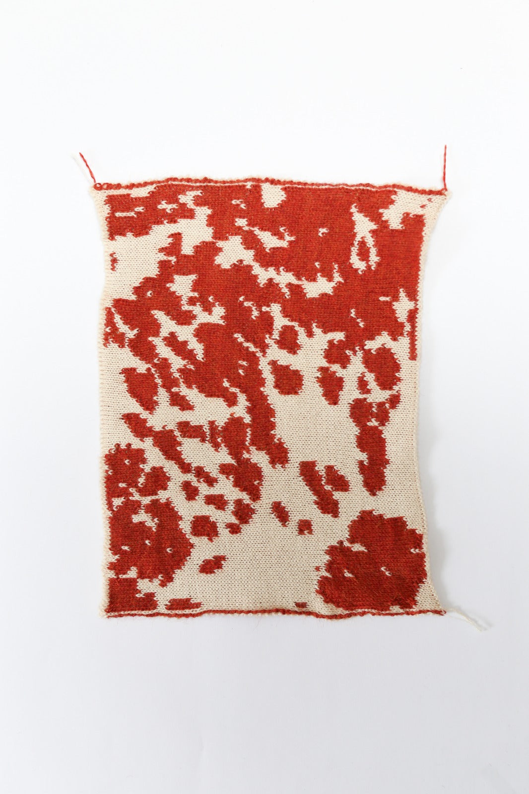 Cow patterned cream and red knit swatch on a white background