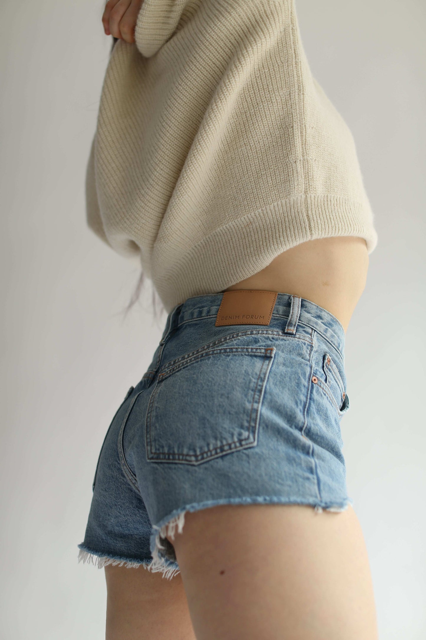 Close-up of a woman wearing jeans shorts and a white sweater