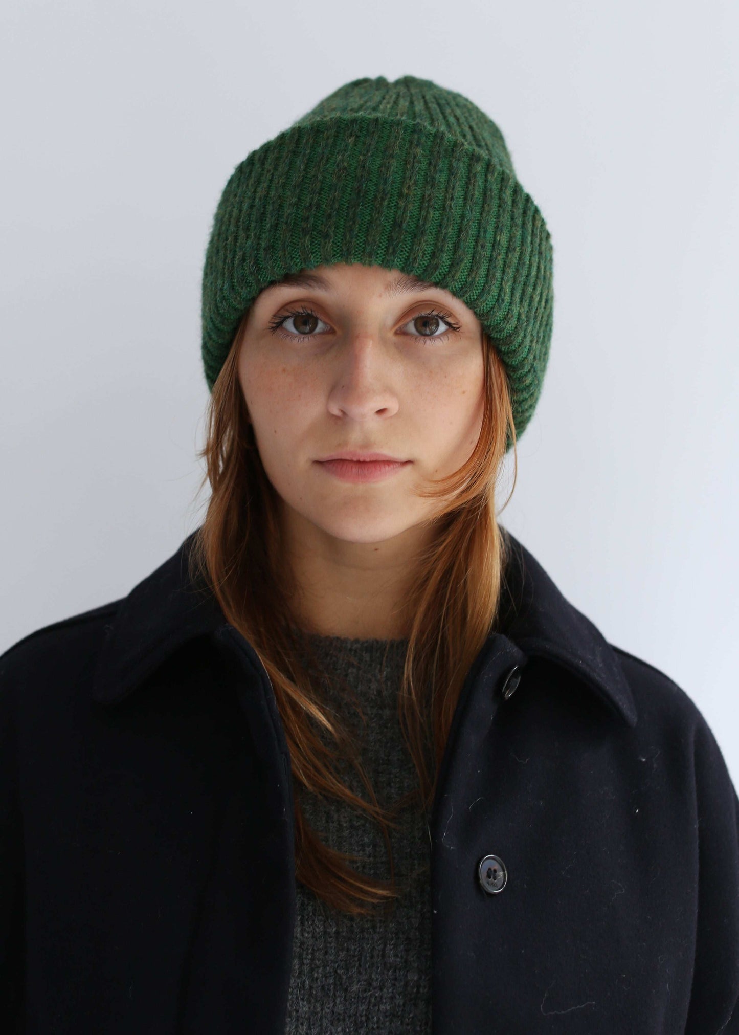 Woman wearing a green beanie wearing a black coat