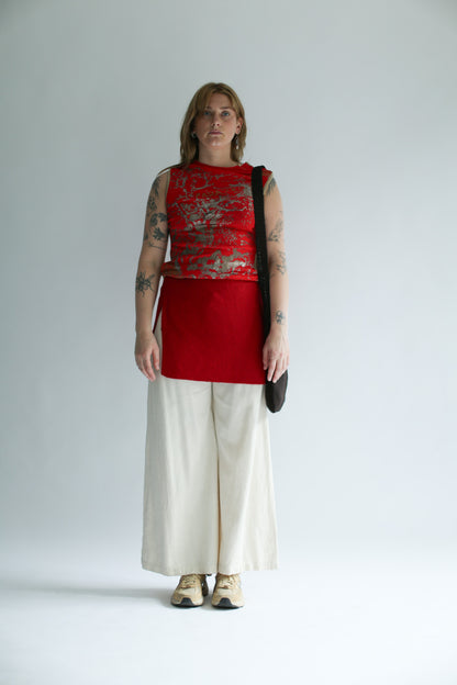 Woman wearing a red knit skirt over a red sleeveless top and wide white pants