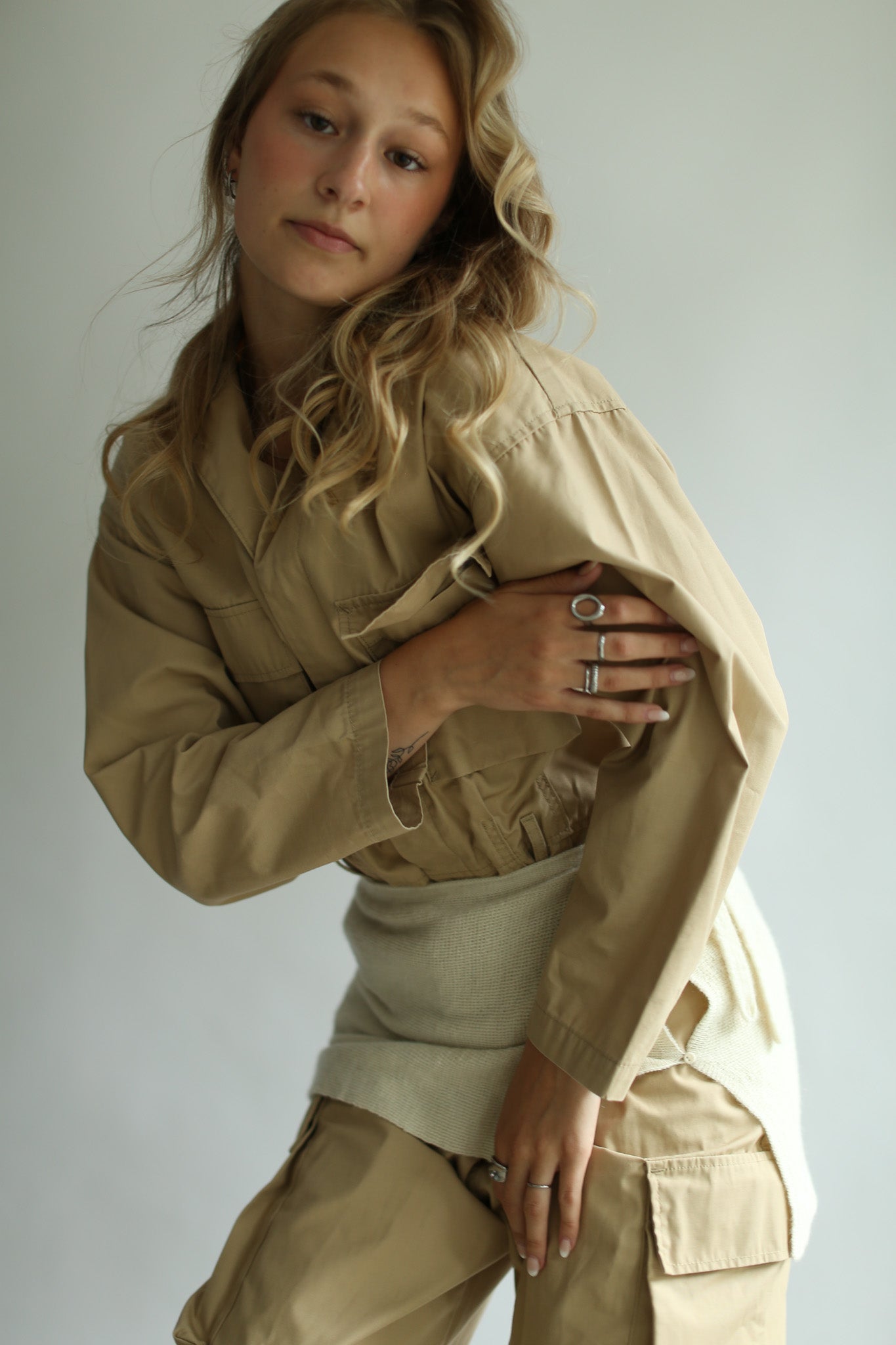 Woman wearing a white skirt over a beige shirt and pants against a plain background
