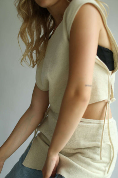 Detail of a woman wearing white sleeveless top and a white knit skirt over a pair of jeans