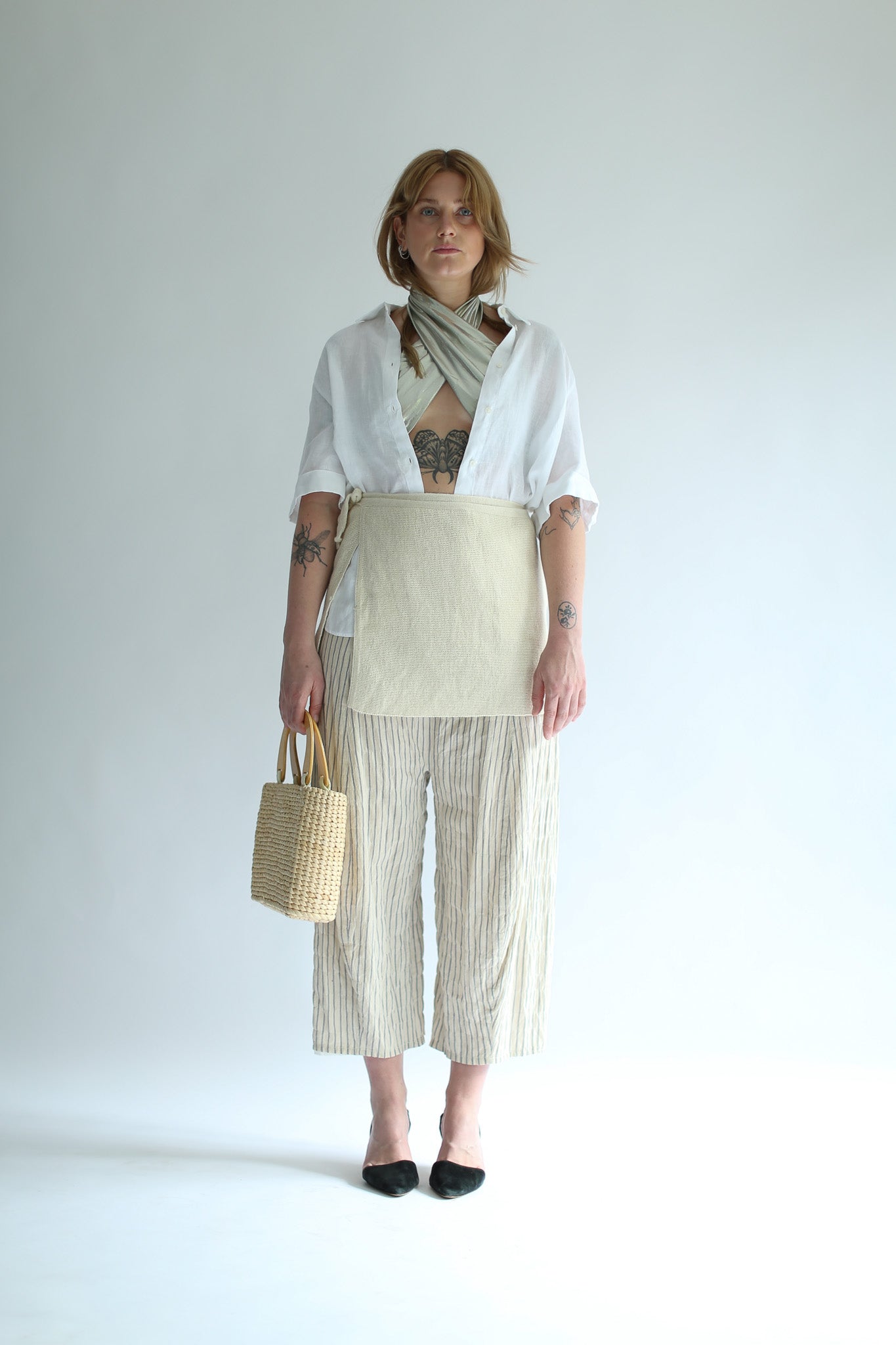 A woman wearing a white knit skirt over striped pants and a white shirt