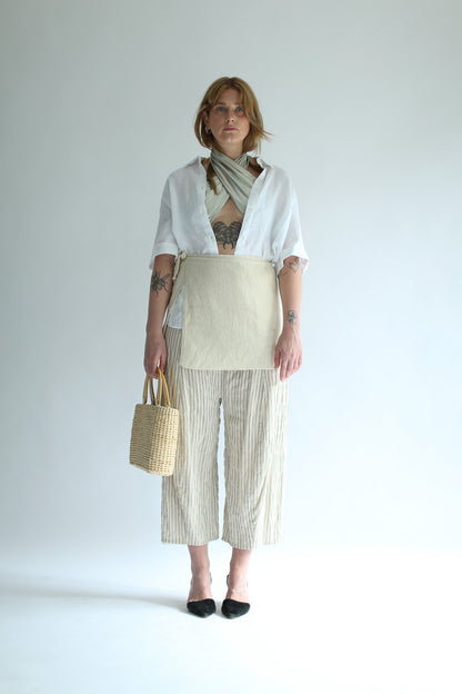 A woman wearing a white knit skirt over striped pants and a white shirt