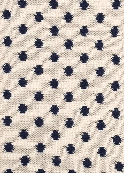 Patterned knit fabric with navy dots on a beige background