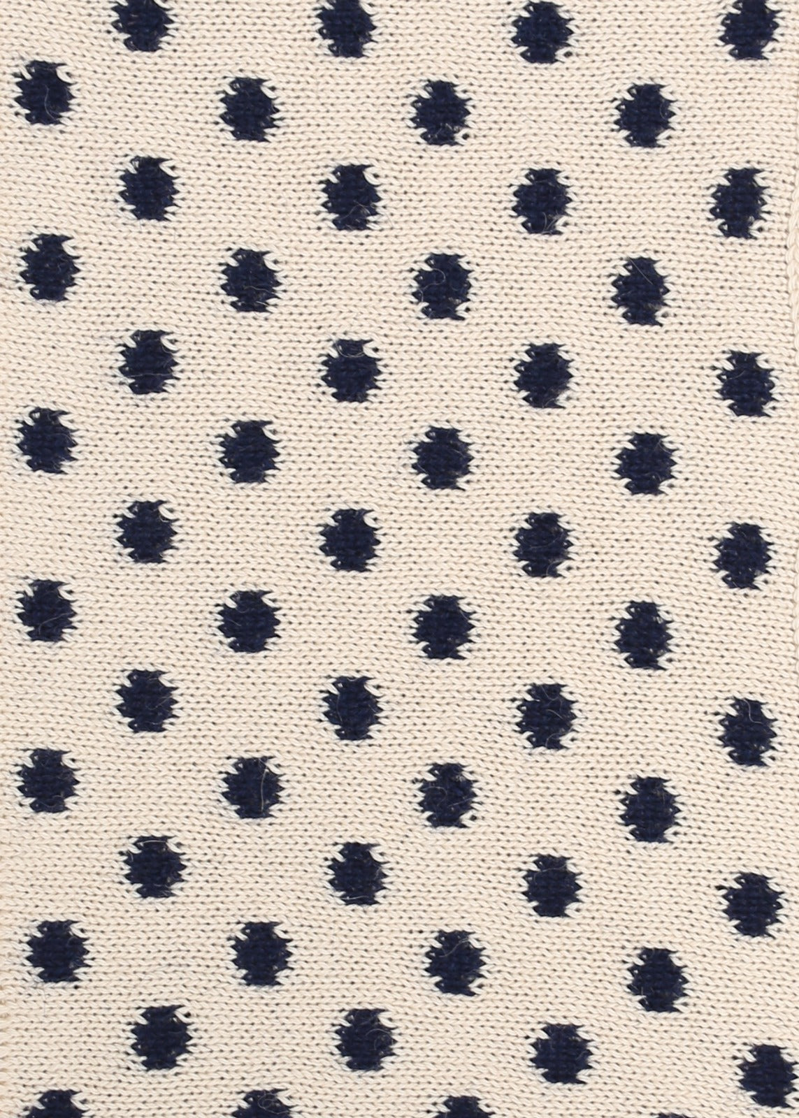 Patterned knit fabric with navy dots on a beige background