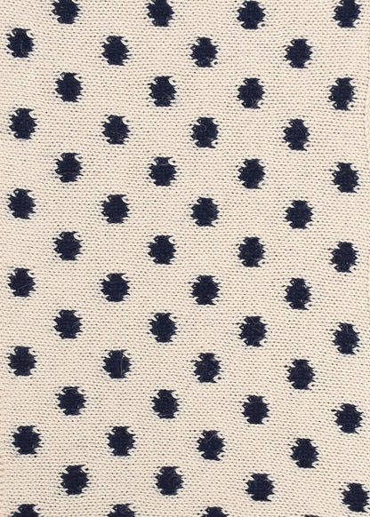 Patterned knit fabric with navy dots on a beige background