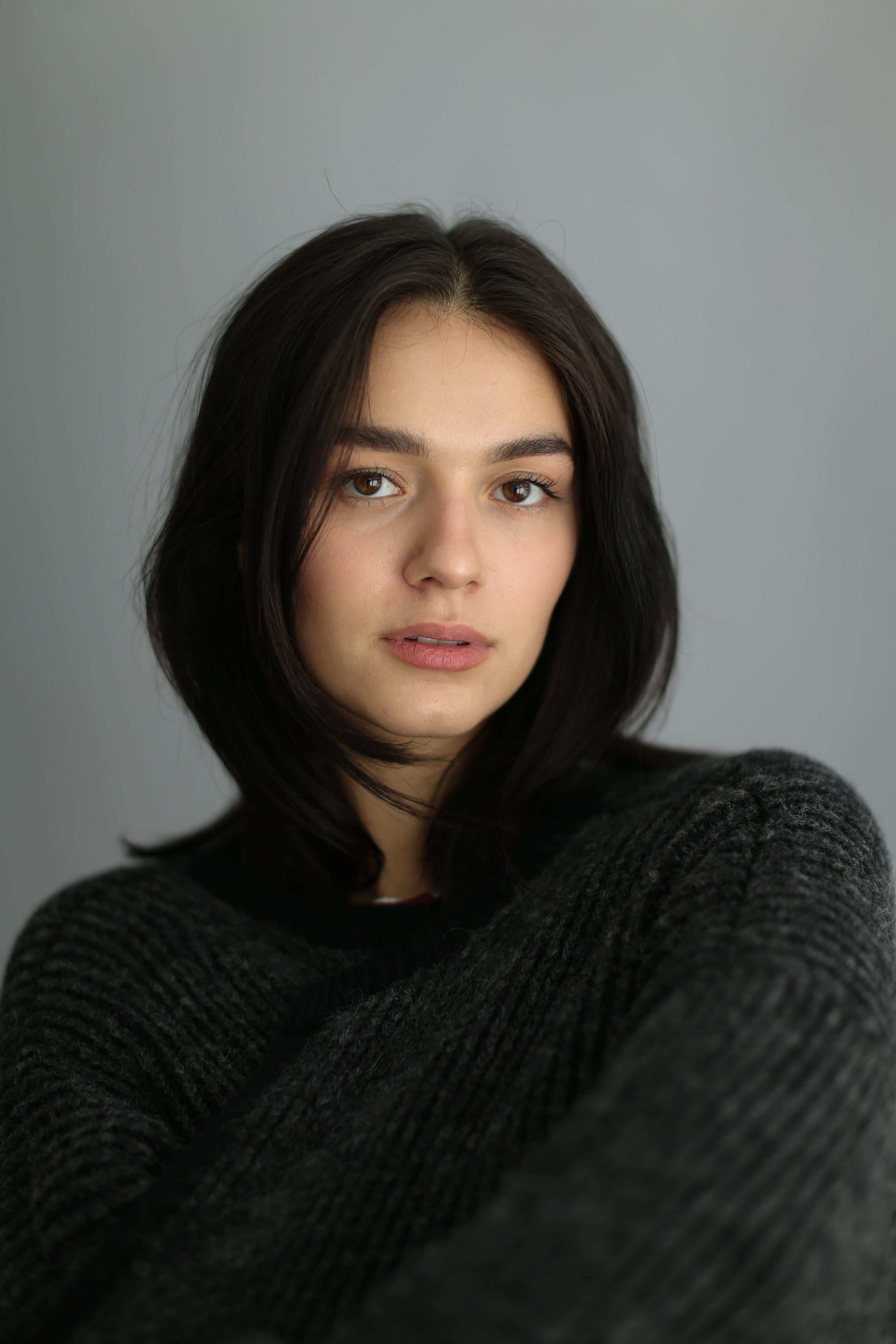 Portrait of a model wearing a grey and black ribbed cardigan
