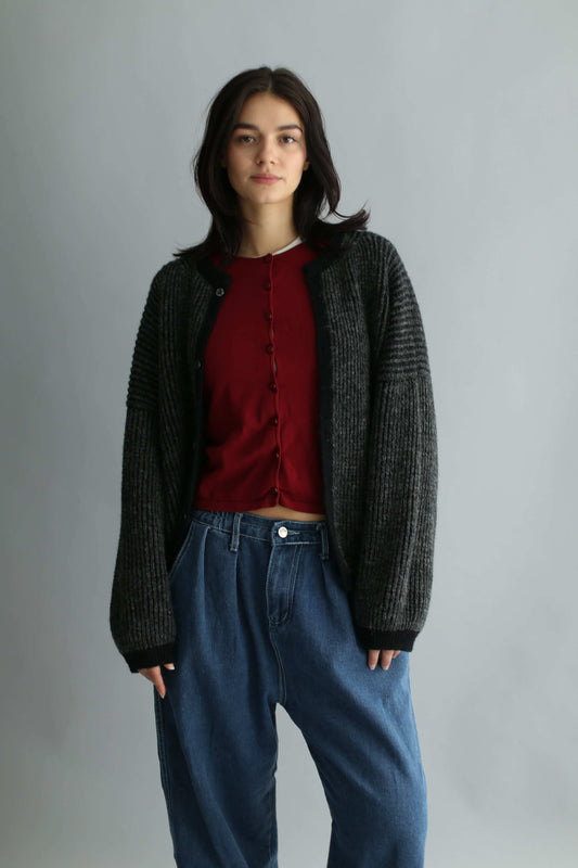 Portrait of a model wearing a grey and black ribbed cardigan with red knit and blue jeans