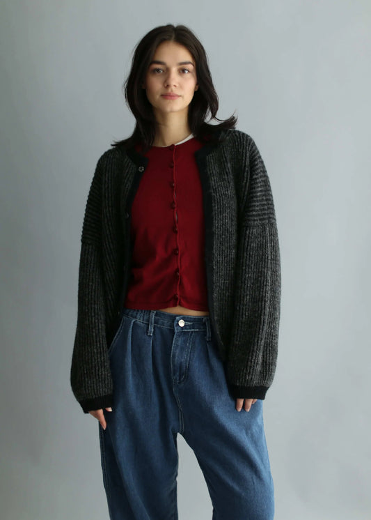 A model wearing an oversize grey and black cardigan over a neutral background