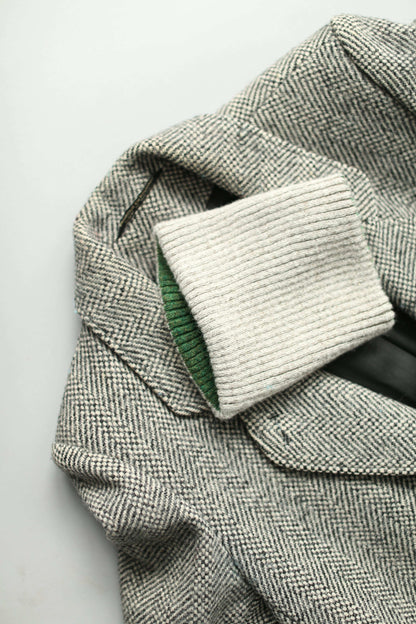 A white and green neck warmer on a grey herringbone coat