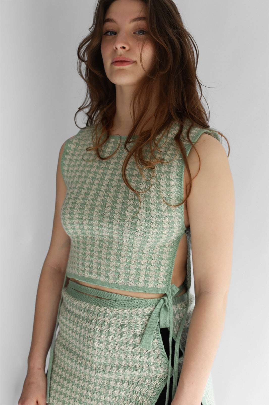 A woman wearing white and green houndtooth knit apron and skirt 