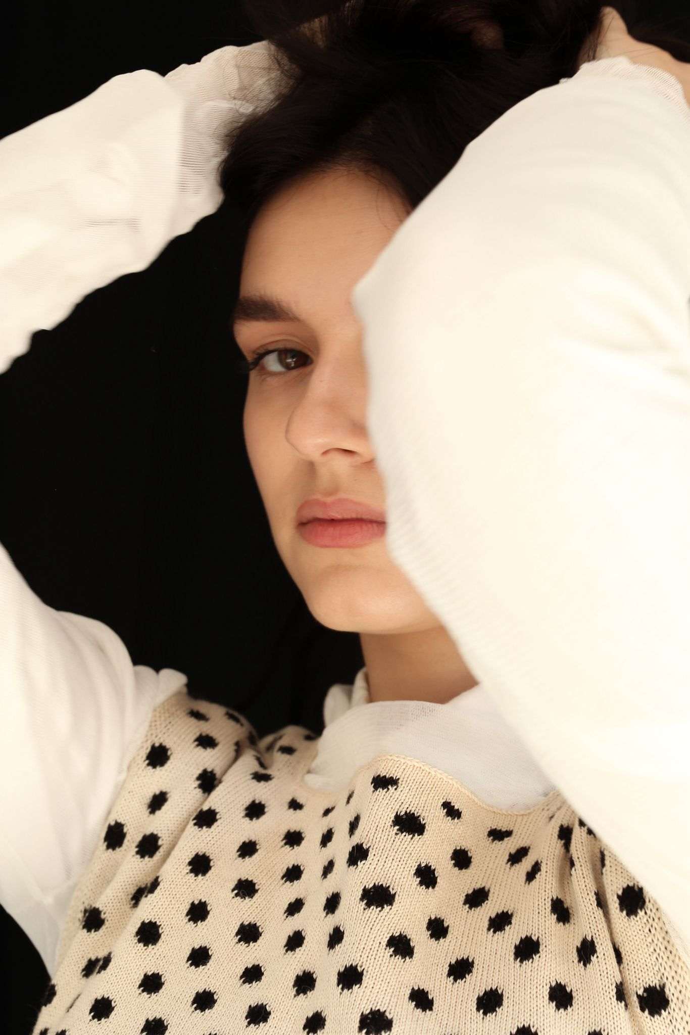 Close-up of a woman wearing a polka dot top against a black background