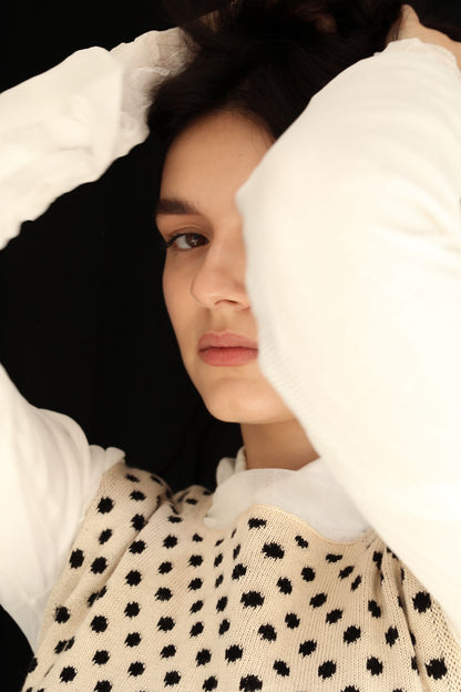 Close-up of a woman wearing a polka dot top against a black background
