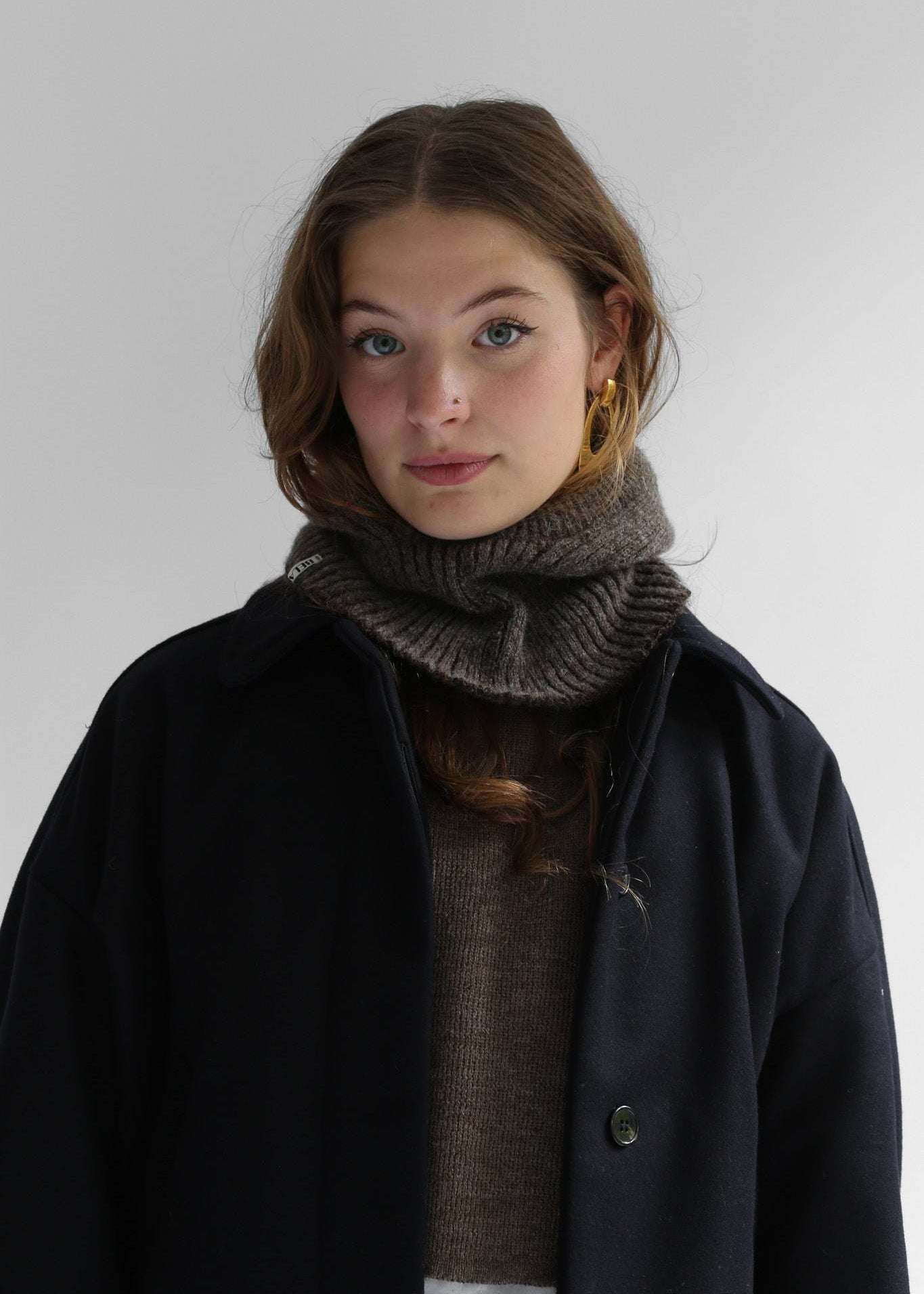 Portrait of a woman wearing a brown balaclava against a white background