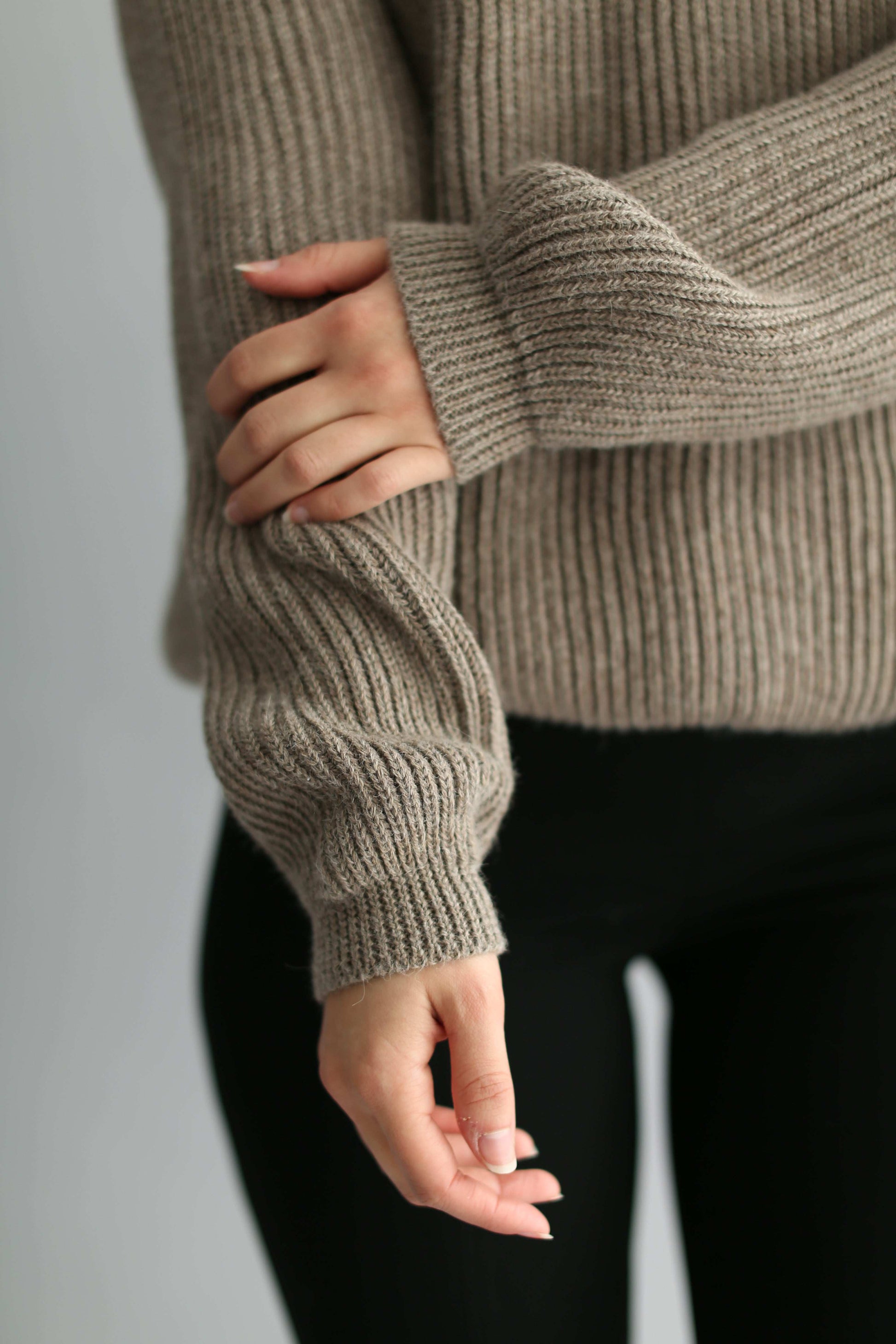 Hands and arms of a model wearing ribbed brown knit
