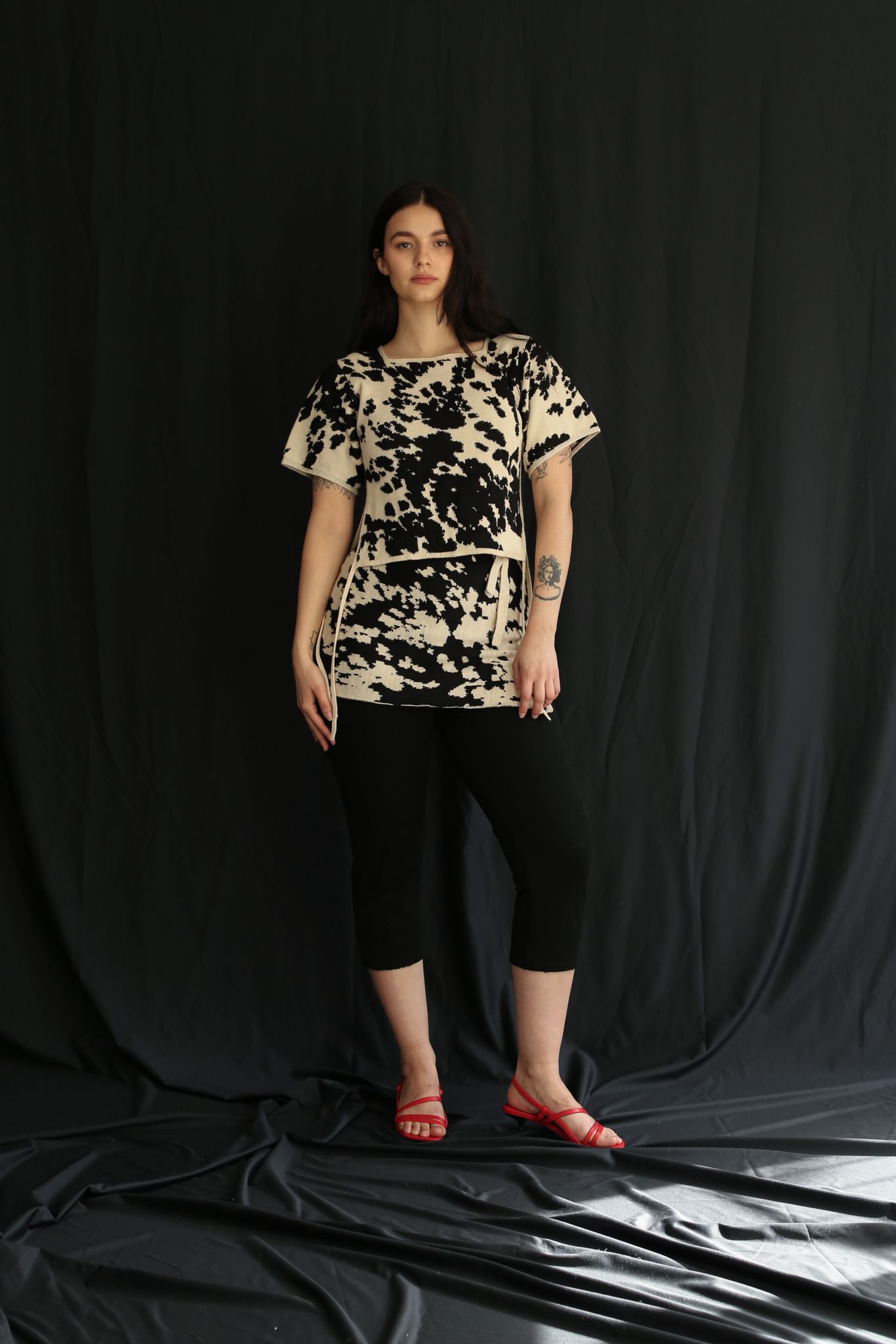 Woman wearing a black and white cow patterned t-shirt and skirt against a black background